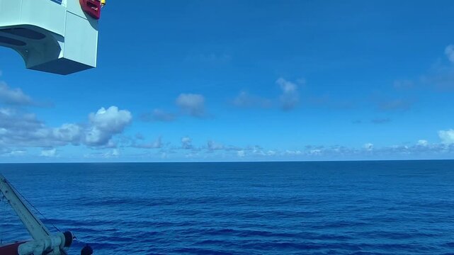 Calm ocean waves under a vast blue sky from a moving ship clip