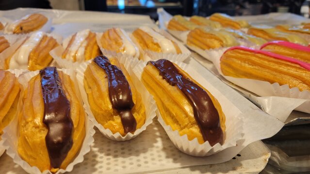 Assorted chocolate and vanilla glazed eclairs displayed at traditional bakery counter