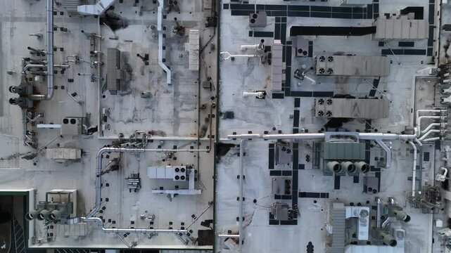 Aerial view of industrial building rooftop with HVAC units and pipes.