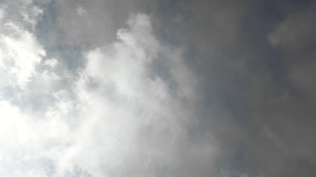 Dramatic stormy cloudscape with dark gray clouds passing over the sun against a bright blue sky