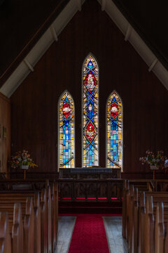 Interior view of St John the Baptist Anglican Church with stained glass windows and red carpet aisle in Waimate North New Zealand