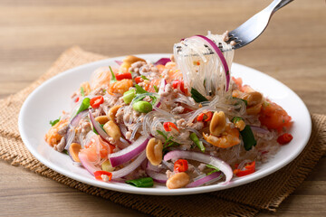 Thai spicy glass noodle salad with minced pork and shrimp (Yum Woon Sen) on a white plate ready to eat © nungning20