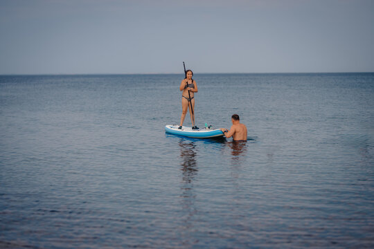 Couple enjoying paddleboarding activity on calm ocean water