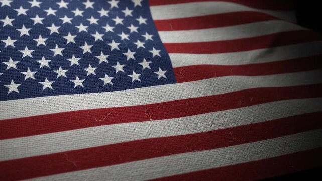 American flag textile background close up with gentle motion and dark edges featuring patriotic woven textures.