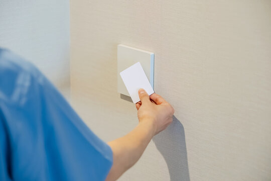 A man holding a card up to a reader. IC card, authentication, touch, key card, security, crime prevention, hotel, entrance.