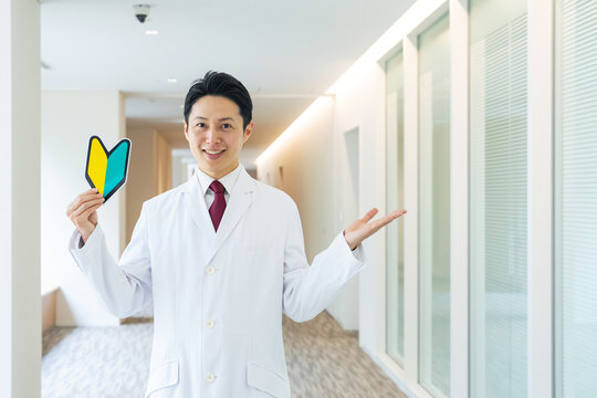 初心者マークを持つ白衣の男性。医師、病院、クリニック、資格、スキル、研修医、新人、採用、セミナー