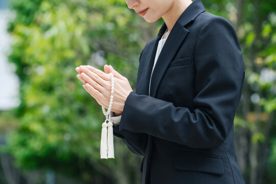 数珠を持って手をあわせる女性。墓地, お墓参り, 供養, 喪服, 葬式, 葬儀, 葬祭場, 樹木葬