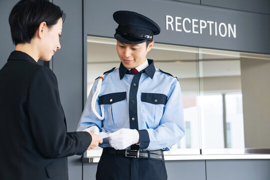 警備員にカードを見せる女性。ID、身分証、社員証、入退室管理、チケット、防犯、セキュリティ、認証
