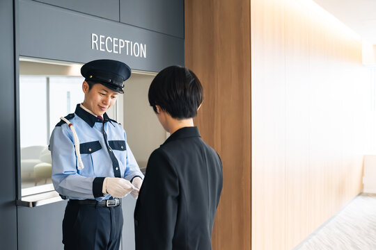 警備員にカードを見せる女性。ID、身分証、社員証、入退室管理、チケット、防犯、セキュリティ、認証