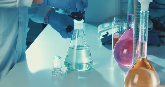 A scientist in blue gloves is conducting an experiment with a flask in a laboratory.