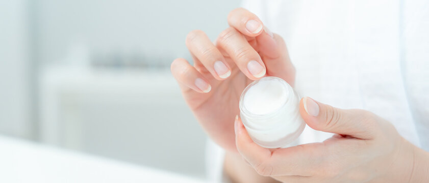 Beautiful Asian woman and close up hand hold cream for good skin. face of a healthy woman apply cream and makeup. Advertisement skin cream, anti-wrinkle, baby face, whitening, moisturizer, serum