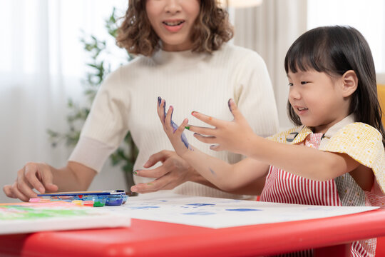 Happy children playing learning paint on paper and hands. Activity, development, IQ, EQ, meditation, brain, muscles, essential skills, family having fun spending time together. Holiday