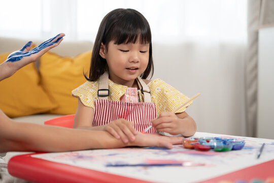 Happy children playing learning paint on paper and hands. Activity, development, IQ, EQ, meditation, brain, muscles, essential skills, family having fun spending time together. Holiday