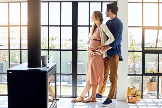 Pregnancy, window and couple in home thinking for prenatal care, bonding and affection for love. House, marriage and man with pregnant woman, embrace and hug for relationship, maternity and support