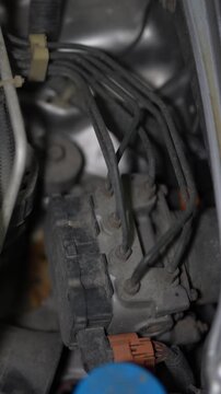 Car ABS hydraulic modulator pump block with connected brake lines.