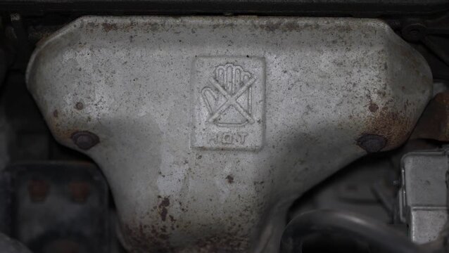 Car exhaust manifold heat shield with a hot warning sign.