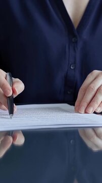 Woman's hand signing a document with a pen, confirming a business agreement, making a legal commitment, completing official paperwork, and taking a crucial step in administrative processes