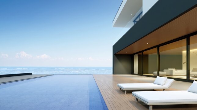 Luxury modern villa with infinity pool overlooking the calm blue ocean, featuring a wooden deck with white sun loungers and large glass windows under a clear sky.
