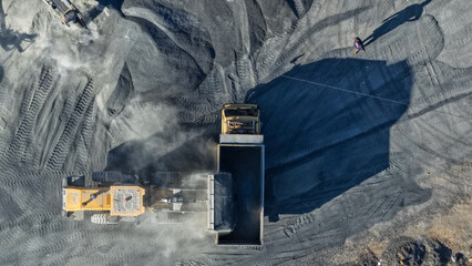 Excavator loading black coal into a large dump truck at a busy industrial mining site in Indonesia © A Denny Syahputra