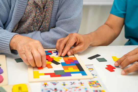 Asian elderly woman playing game with caregiver for train memory.
