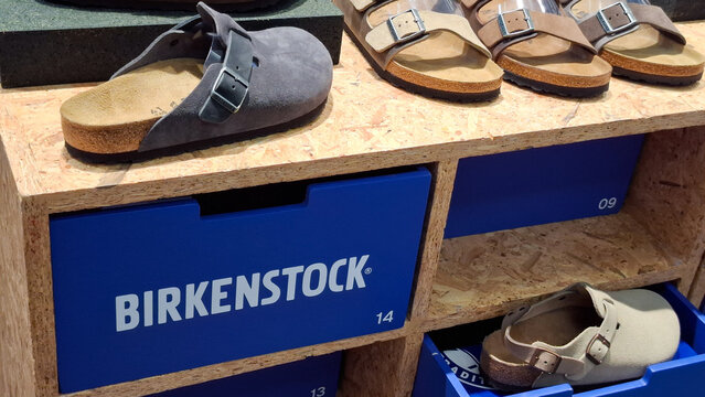 Variety of Birkenstock cork sole sandals and clogs on wooden retail display with blue shelf boxes in clothing store on July 27, 2026 in Bangkok, Thailand 