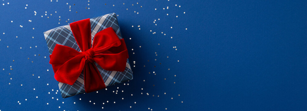 Merry Christmas and Happy New Year celebration with Santa Claus present wrapped in red bow on blue background