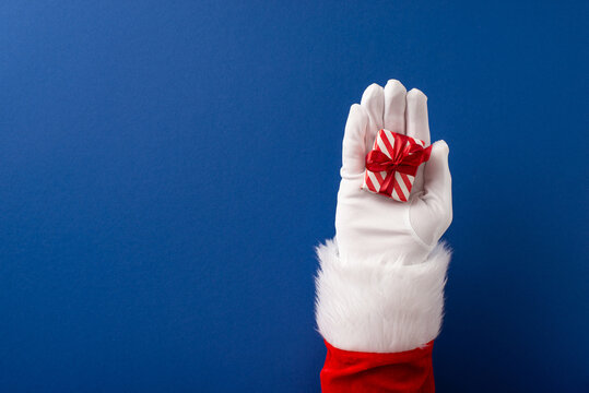 Merry Christmas and Happy New Year from Santa Claus holding a tiny wrapped gift with red bow