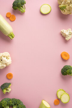 Baby's first feeding with fresh vegetables for healthy baby food on pastel pink background