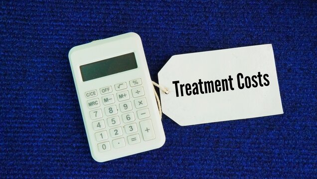 Calculator and paper tags with the word Treatment costs. the total financial expense required to diagnose, manage, and cure a medical condition or health issue.