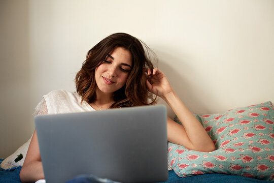 Relax, girl and smile on bed with laptop, online movie and binge watch series on weekend break. Chill, happy woman or tech in home bedroom for streaming subscription, tv show or unwind with hairplay