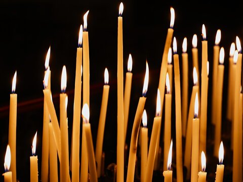 Vue rapproch&eacute;e d'un groupe de cierges verticaux allum&eacute;s dans un &eacute;difice religieux et formant une multitude de flammes cr&eacute;ant une ambiance chaleureuse. Lumi&egrave;res d'espoir.