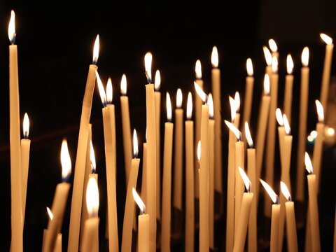 Vue rapproch&eacute;e d'un groupe de cierges verticaux allum&eacute;s dans un &eacute;difice religieux et formant une multitude de flammes cr&eacute;ant une ambiance chaleureuse. Lumi&egrave;res d'espoir.