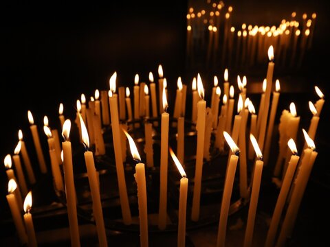 Vue rapproch&eacute;e d'un groupe de cierges verticaux allum&eacute;s dans un &eacute;difice religieux et formant une multitude de flammes cr&eacute;ant une ambiance chaleureuse. Lumi&egrave;res d'espoir.