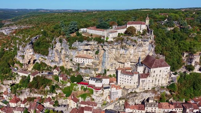 Drone rises and retreats revealing Rocamadour village built into rocky cliffs