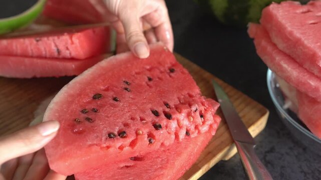 A woman's hands slice and peel a watermelon. Side view, close-up. Healthy lifestyle concept.