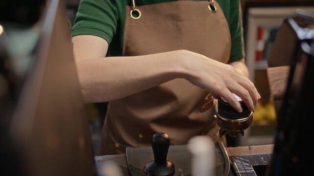 Barista leveling ground espresso with distributor tool and tamping portafilter in cafe. Ideal for coffee brand advertising and barista training tutorials