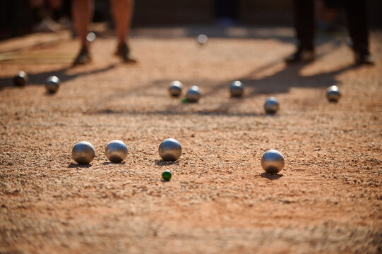 Petanque Boules and Green Jack Target Ball with Players in Background