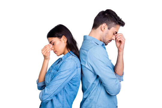Two entrepreneurs overworked holding their fingers on nose between eyes, relationship of young family came to the dead end, standing over grey background