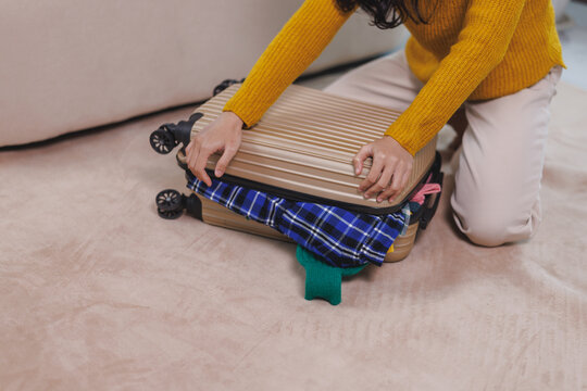 Woman packing overfilled suitcase preparing for travel