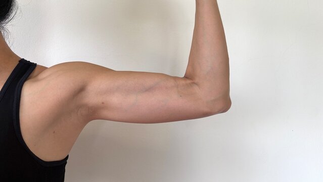 Close up , strong arm muscle rigtht side of a fitness woman , white background.