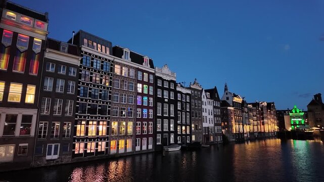 A typical scene with canal-side houses along the Damrak in Amsterdam, Netherlands, at night