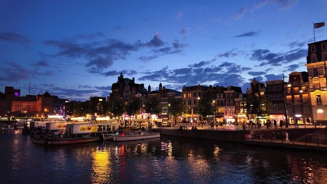 Damrak with canal houses along the canal and hopping district of Amsterdam, Netherlands, at night
