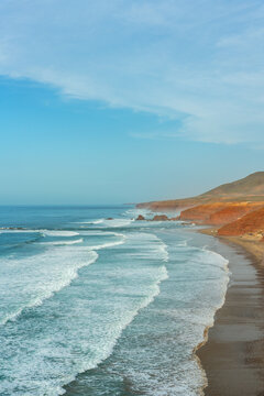 Legzira beach coastline with red cliffs and Atlantic waves in Morocco