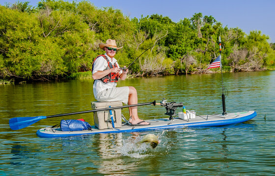 Man catches a jumping bass from his fishing paddleboard