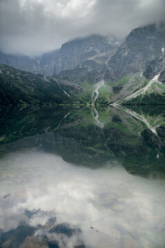 Morskie Oko lake reflects dramatic Tatra mountains under cloudy skies
