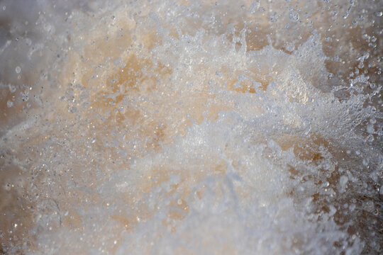 Churning white water creating energetic splashes, foam, and floating water droplets.