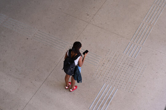 African American woman standing on tactile paving floor looking