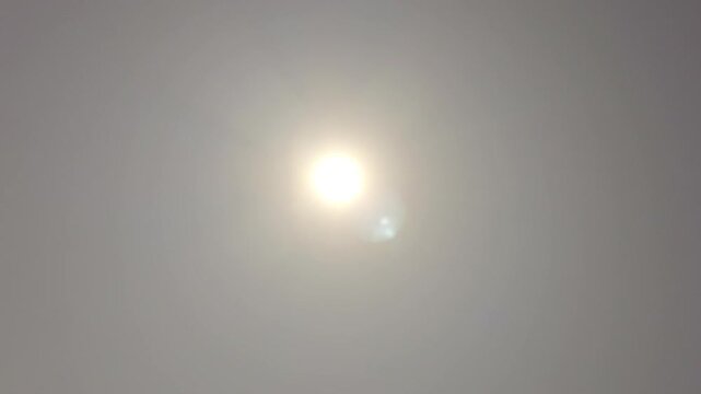 Sun glowing behind dense fog and atmospheric haze on overcast day