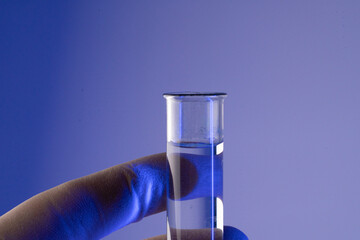 Chemist hand in glove holding test tube with blue liquid during longevity research in a modern...