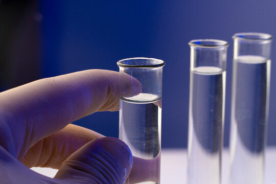 Researcher holding glass test tube with clear solution for aging and longevity research in modern science laboratory